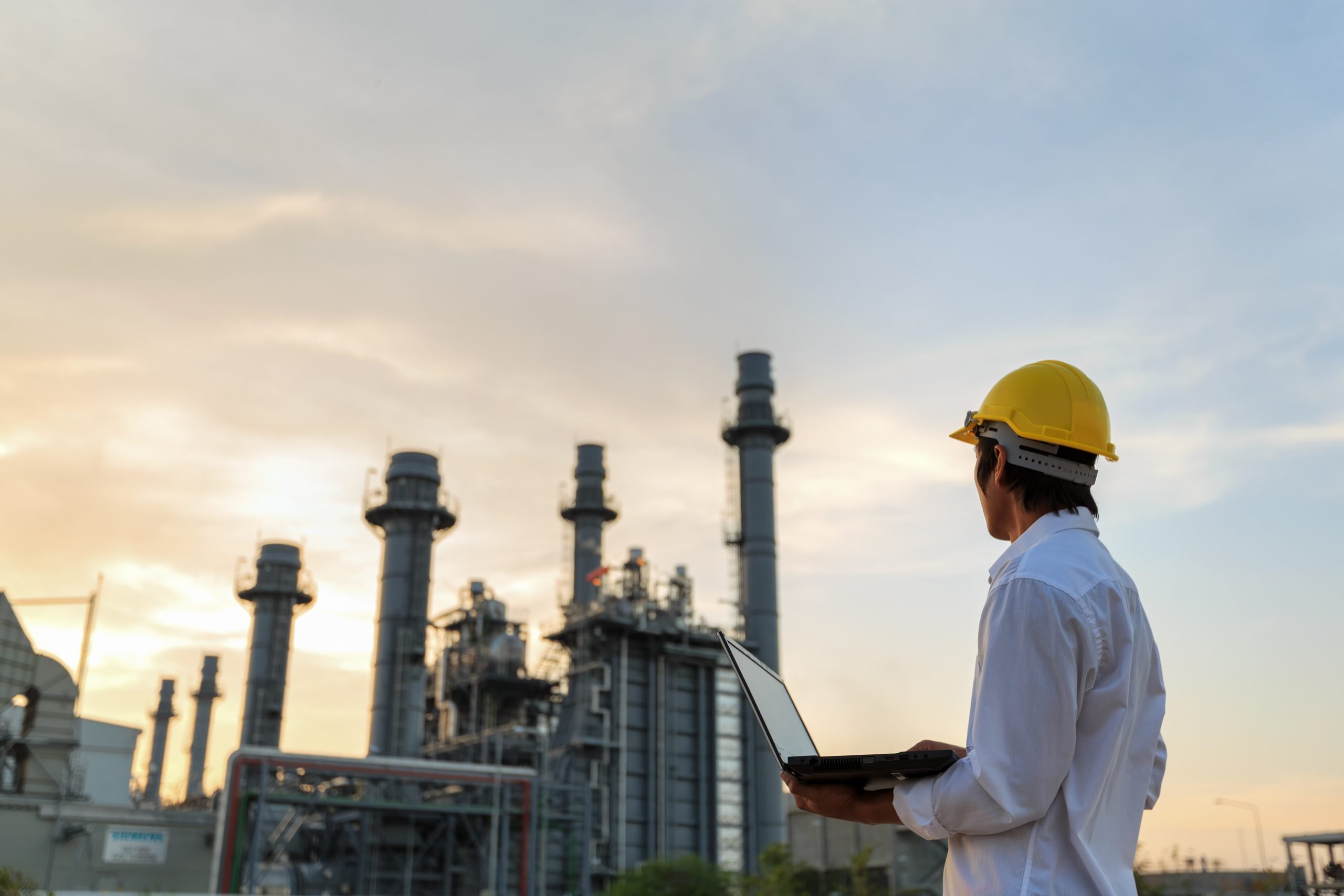 Biofuel plant operations manager reviewing facility performance at sunset as part of biofuel succession planning and regulatory continuity strategy