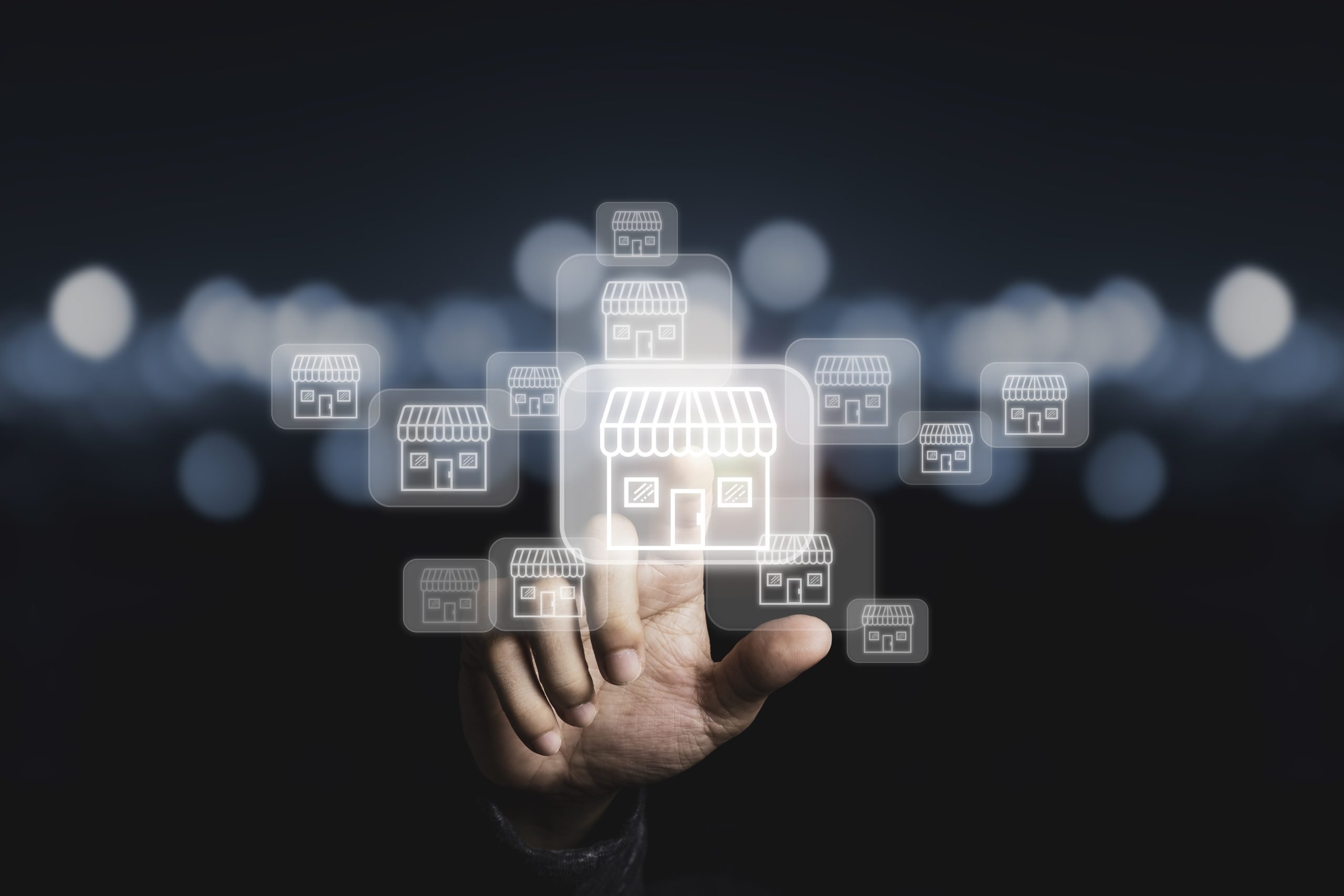 Businessman hand pointing to virtual shopping store which connection line with others small shopping stores , expand and development franchise concept.