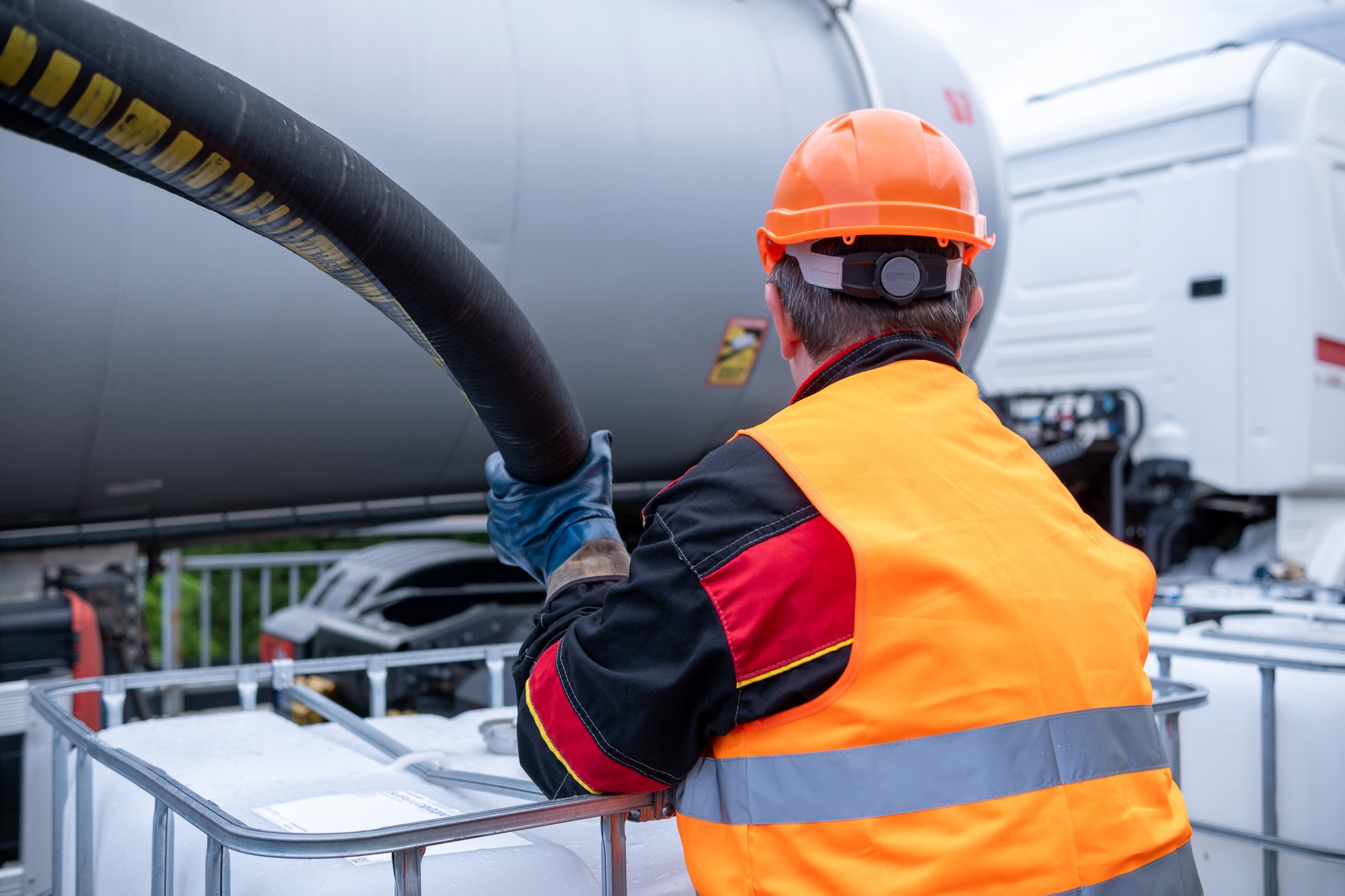 Fuel delivery worker handling a tanker hose, representing succession planning for HVAC and fuel delivery businesses and energy distribution continuity.
